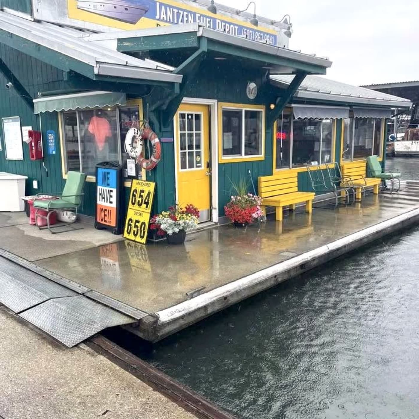 The Jantzen Fuel Depot dock building, forest green with yellow trim, with the fuel price sign showing unleaded and diesel prices